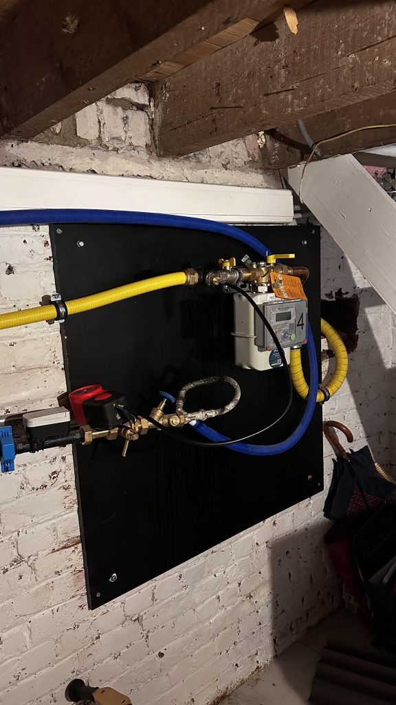 Remise en ordre et sécurisation d’une arrivée de gaz en cave à Bruxelles, réalisée par le chauffagiste Fluviotherm avec pose d’un panneau support, de vannes accessibles et de raccords conformes.